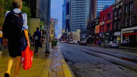 Street-scene-after-rain-fall-fat-pedestrians-traffic-cyclist-eye-level-Wellesley-Yonge-Street-brick-old-buildings-in-the-foreground-overshadowed-by-modern-glass-architecture-in-the-background