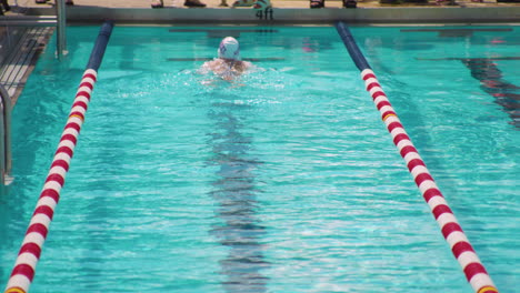 Swimmer-athlete-butterfly-stroke-technique-in-swimming-pool,-tilt-up-reveal