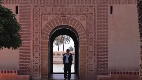 A-local-strolling-through-the-historical-old-town-of-Marrakesh,-surrounded-by-the-charm-of-ancient-facades-and-immersed-in-the-rich-arab-architecture-while-slowly-walking-through-a-gate