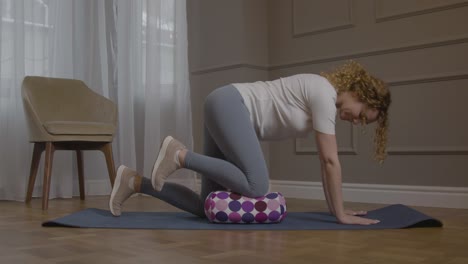 Caucasian-Women-Placing-knee-On-Pillow-On-Yoga-Mat-And-Lifting-Left-Leg-In-Air