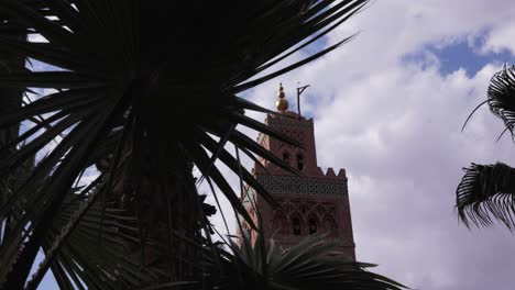 A-steady-shot-of-an-ancient-minaret-framed-by-lush-palm-leaves-–-an-iconic-view-of-Marrakesh's-historic-beauty-of-a-famous-mosque-in-the-medina