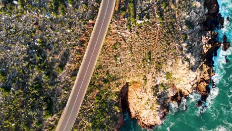 Drone-footage-of-a-long-winding-road-leading-past-the-sea