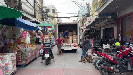 Workers-unloading-goods-from-the-truck-in-Yaowarat-Chinatown,-Bangkok,-Thailand