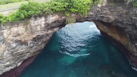 Waves-of-turquoise-clear-water-break-through-natural-arch-bridge-of-Broken-Beach-on-Nusa-Penida-island