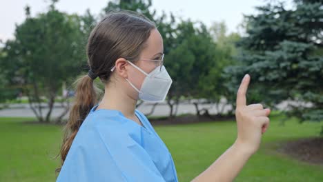 Young-nurse-with-face-mask-showing-NO-sign-with-her-hand,-side-view