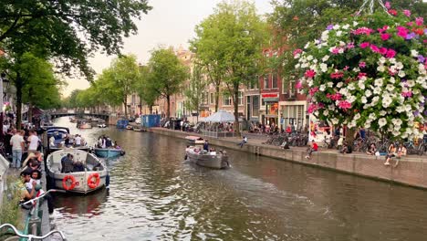 Wunderschöne-Amsterdamer-Landschaft-Im-Sommer-Mit-Booten-Auf-Dem-Kanal-Und-Bunten-Blumen