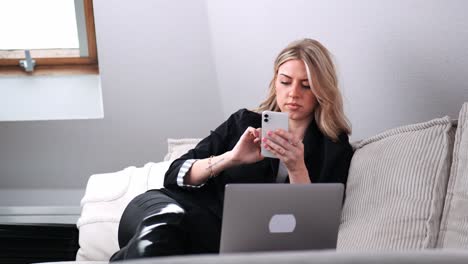 A-young-businesswoman-sits-on-the-sofa-and-surfs-on-her-smartphone
