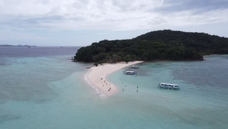 People-on-Ditaytayan-island-sandbar-in-Coron,-Philippines-with-island-hopping-Boats-in-blue-clear-water