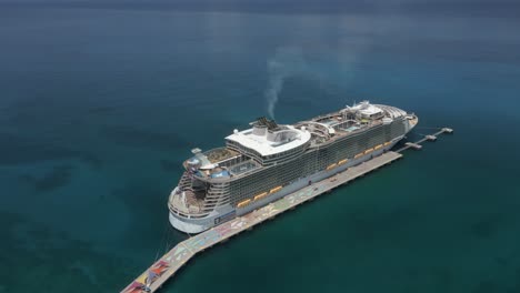 Tourism:-Aerial-orbits-large-cruise-ship-at-pier-in-shallow-azure-sea