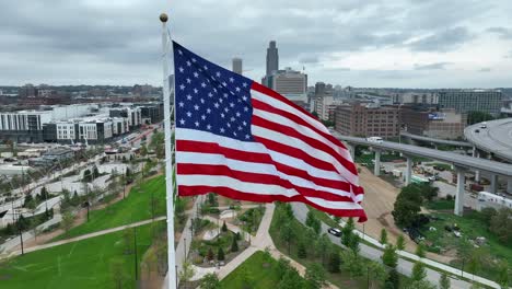American-flag-waving-high-above-Omaha-riverfront-parks-and-skyline