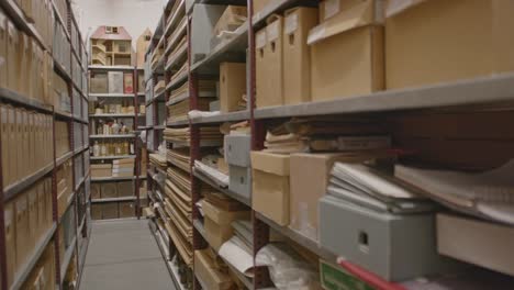 Pan-over-aisle-of-archive-with-cardboard-boxes-and-files