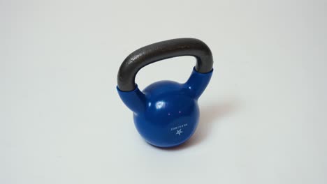 Blue-Kettle-bell-free-weight-work-out-gym-equipment-tool-against-a-white-background