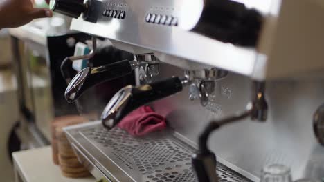 Barista-cleaning-portafilter-on-coffee-machine-by-trun-on-steaming