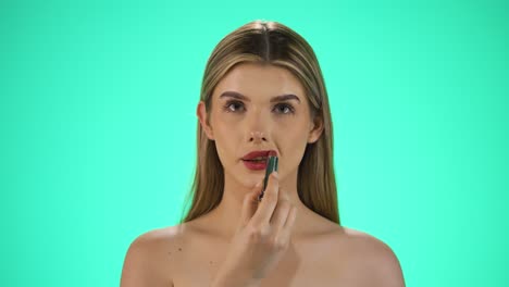 Slow-motion-shot-of-a-young-attractive-caucasian-blonde-woman-while-applying-red-lipstick-on-her-lips-to-get-ready-for-the-evening-or-date-while-looking-sexy-to-the-camera