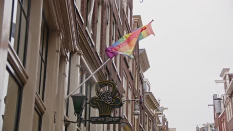 Pride-flags-flying-on-the-facade-of-a-gay-bar-in-Amsterdam,-the-Netherlands