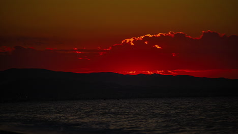 Zeitraffer-Eines-Goldenen-Sonnenaufgangs-Am-Strand-Mit-Bergen-Im-Hintergrund