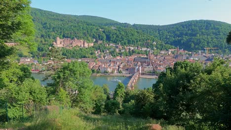 Hillside-view-of-Heidelberg-city-center-in-Germany-at-Neckar-river-with-castle-palace-and-Theodor-Bridge-in-a-long-wide-shot