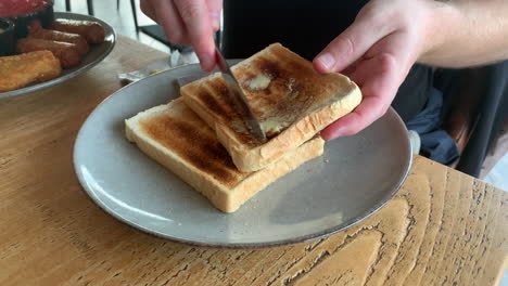 Ein-Mann-Beschmiert-Toast-In-Einem-Café-Restaurant-Beim-Frühstück-Mit-Einem-Messer