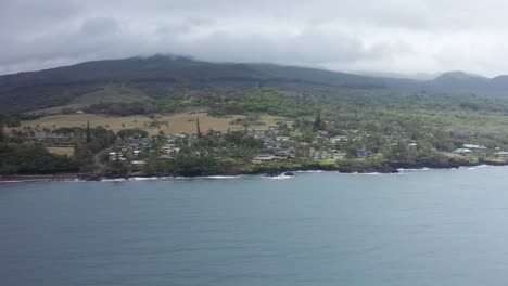 Aerial-low-panning-shot-flying-over-Hana-Bay-towards-the-small-town-of-Hana-on-the-windward-coast-of-Maui,-Hawai'i