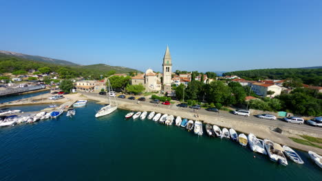Drone-soars-swooping-FPV-through-sailboat-masts-over-town-city-center-of-Osor-Croatia