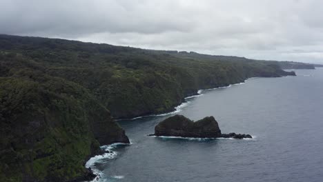 Low-descending-aerial-shot-of-the-rugged-coastline-along-the-Road-to-Hana-in-Maui,-Hawai'i