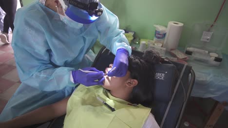 Dentist-woman-treats-a-little-girl-during-a-medical-brigade-in-an-improvised-clinic,-in-a-school-in-a-poor-community