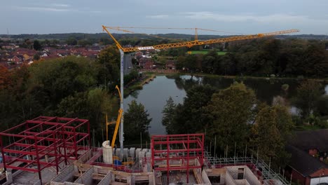 Aerial-view-rising-across-care-home-construction-development-framework-in-rural-British-village-next-to-fishing-lake