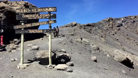 At-the-summit-of-Mount-Kilimanjaro-in-Africa's-Tanzania,-with-individuals-in-the-backdrop
