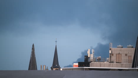 Light-fades-as-smoke-blows-over-roofs-in-Antwerp,-Belgium