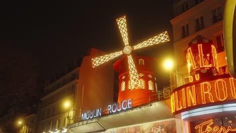 Illuminated-windmill-at-Moulin-Rouge-casts-a-warm-glow-over-bustling-streets-of-Paris