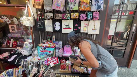 Hispanic-woman-shopping-for-Japanese-products-from-a-street-market-vendor-in-Little-Tokyo,-Los-Angeles