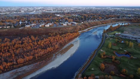 A-drone-view-of-orange-trees,-Bow-River,-and-a-golf-course-in-Calgary