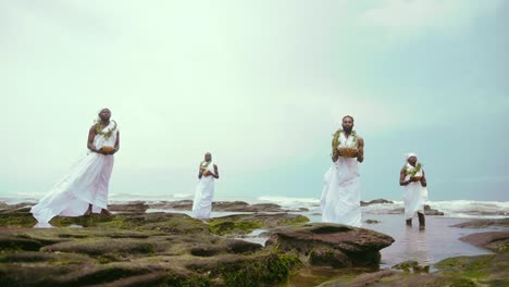 4-Tradicionalistas-Africanos-Ga-Sosteniendo-Calabaza-Realizando-Rituales-Y-Libaciones-En-Rocas-Al-Lado-Del-Mar