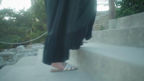 mid-shot-of-person-walking-up-steps-in-white-sandals-and-dress