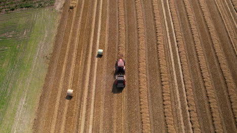 Aerial-shot-of-Agriculture-Tractor-Collecting-Hay-with-Trailed-Bale-Machine