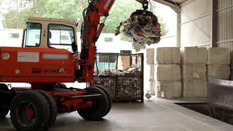 Tractor-operator-moving-paper-from-container-to-conveyor-belt-at-recycling-plant
