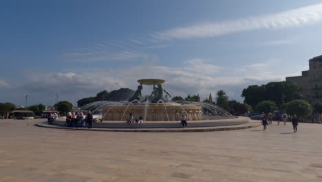 Slow-motion-shot-of-tourists-walking-by-the-Triton-Fountain-in-Valletta-Malta
