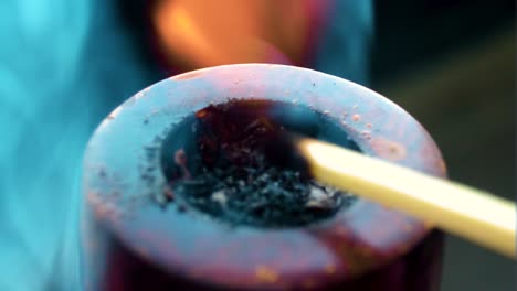 close-up-of-a-match-being-lit-against-a-wooden-modern-colourful-pipe-burned-from-the-flames-tobacco-set-on-fire-burning-inside-smoker-puffing-quality-leaf's-clouds-of-smoke-around-the-item-indoor
