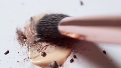 Blending-a-dark-brown-toned-mascara-loose-powder-using-an-eyelash-wand-applicator-on-a-blank-white-board
