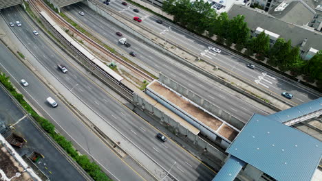 High-angle-view-of-busy-multilane-motorway-and-subway-trains-passing-on-tracks-in-middle