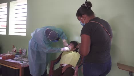 Una-Dentista-Inspecciona-La-Boca-Y-Los-Dientes-De-Un-Niño-Pequeño-Durante-La-Consulta-En-Una-Brigada-Médica-Móvil.