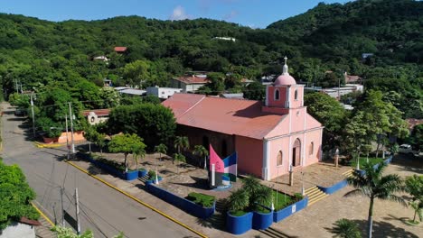 Aerial-orbit-around-purple-catholic-church-in-tropical-city-San-Juan-del-Sur