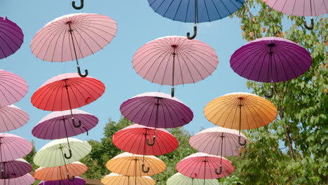 Bunte-Regenschirme,-Die-Beim-Sommersity-Festival-Am-Blauen-Himmel-Hängen---Zeitlupen-Dolly-In-Niedriger-Winkelansicht