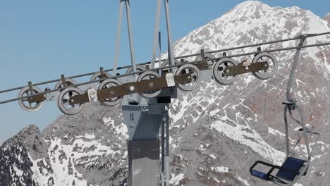 Mecanismo-De-Esquí-Del-Teleférico-Con-Góndolas-Que-Pasan-Con-Fondo-De-Pico-De-Montaña-Nevado