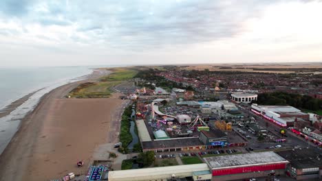 High-above,-video-footage-offers-a-view-of-the-captivating-sunset-scene-over-Skegness,-a-quaint-coastal-town-in-the-UK,-with-the-town,-promenade,-pier,-and-coastline-in-the-shot
