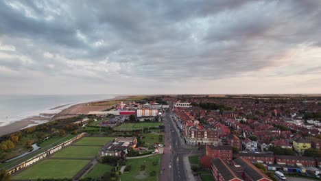 High-above,-video-footage-provides-a-view-of-a-stunning-sunset-scene-over-Skegness,-a-delightful-coastal-town-in-the-UK,-with-the-town,-promenade,-pier,-and-coastline-on-display