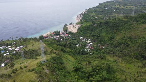 Torres-De-Transmisión-De-Líneas-Eléctricas-Sobre-El-Pueblo-Costero-Entre-El-Verde-Terreno-Costero-Tropical-En-La-Isla-De-Cebú,-Filipinas