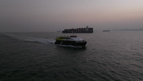 Servicio-De-Ferry-Catamarán-De-Vela-Rápida-Con-Un-Buque-Portacontenedores-Al-Fondo