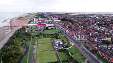 Above-the-town,-video-footage-reveals-the-allure-of-a-sunset-over-Skegness,-a-coastal-town-in-the-UK,-featuring-the-town,-promenade,-pier,-and-the-stunning-coastline