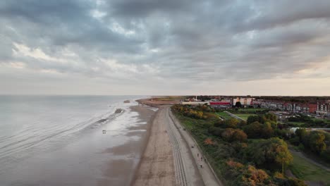 Aerial-video-showcases-the-beauty-of-a-serene-sunset-over-Skegness,-a-charming-seaside-town-in-the-UK,-with-an-emphasis-on-the-town,-promenade,-pier,-and-coastline